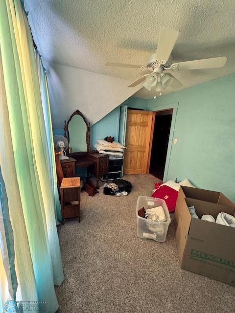 bedroom featuring ceiling fan, lofted ceiling, carpet, and a textured ceiling