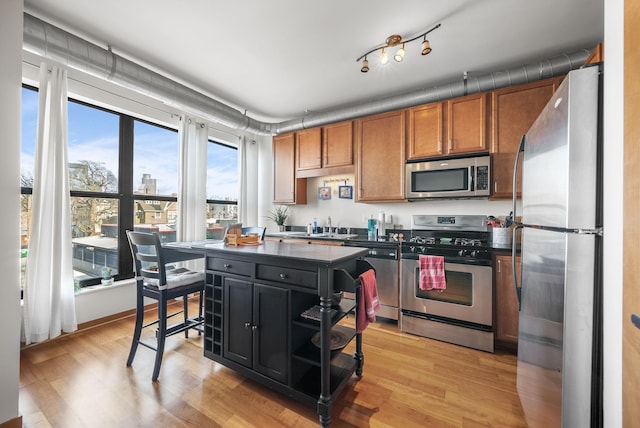 kitchen with sink, light hardwood / wood-style flooring, stainless steel appliances, and a kitchen island