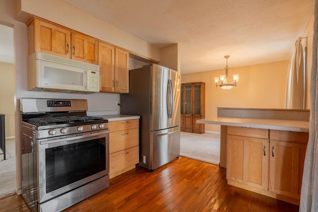 kitchen with pendant lighting, an inviting chandelier, stainless steel appliances, a textured ceiling, and dark hardwood / wood-style flooring