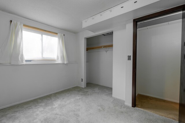 unfurnished bedroom with light colored carpet, a closet, and a textured ceiling