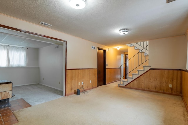 carpeted spare room with a textured ceiling and wood walls