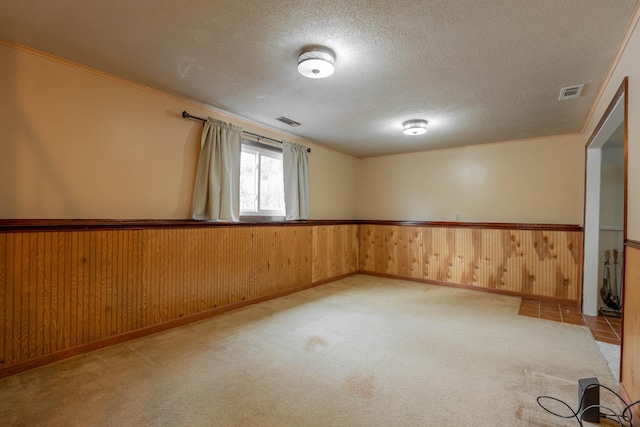unfurnished room with wooden walls, light carpet, and a textured ceiling