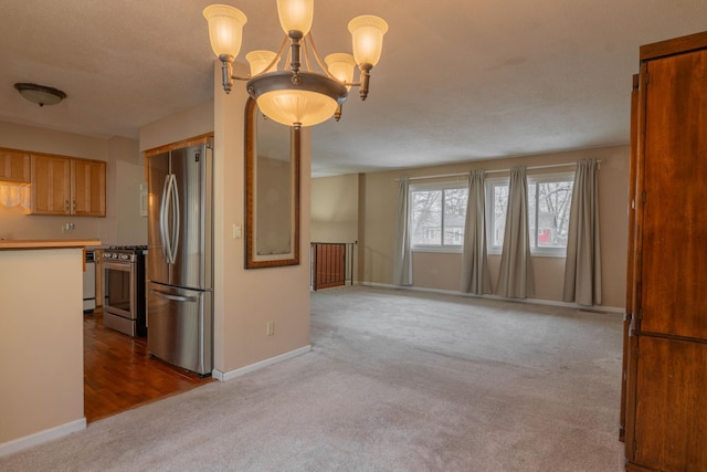kitchen with appliances with stainless steel finishes, carpet flooring, an inviting chandelier, and decorative light fixtures