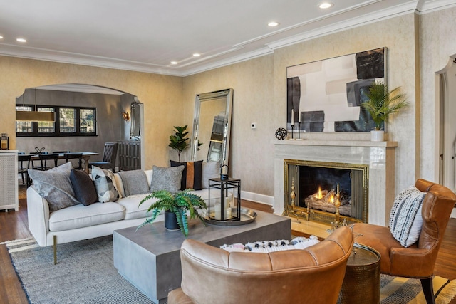 living room with hardwood / wood-style flooring, crown molding, and a high end fireplace