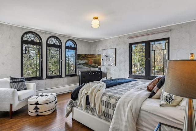 bedroom with hardwood / wood-style floors, french doors, and a baseboard heating unit