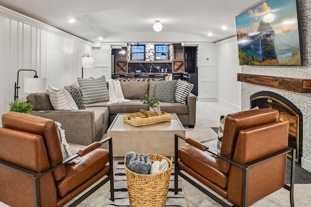 carpeted living room with a stone fireplace and vaulted ceiling