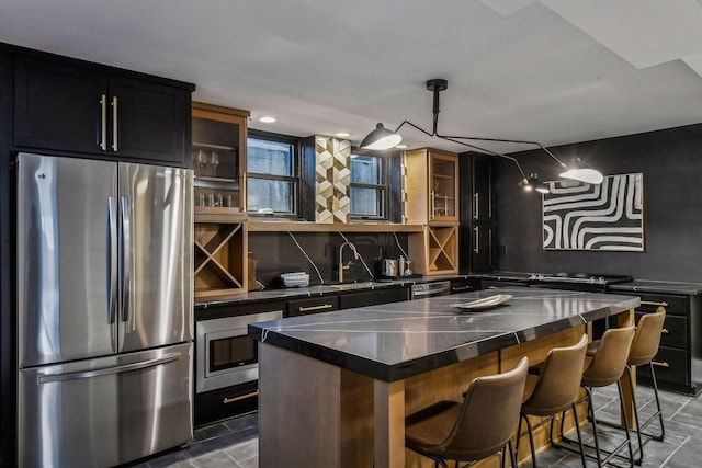 kitchen featuring a breakfast bar, sink, a center island, hanging light fixtures, and appliances with stainless steel finishes