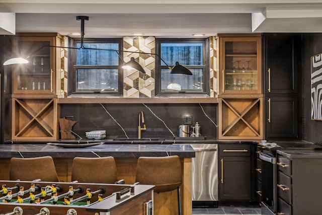 bar with pendant lighting, appliances with stainless steel finishes, sink, and decorative backsplash