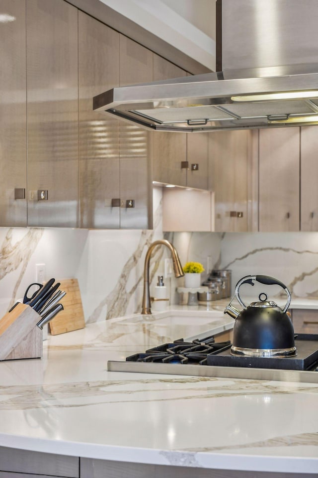 kitchen featuring island range hood, light stone countertops, sink, and backsplash