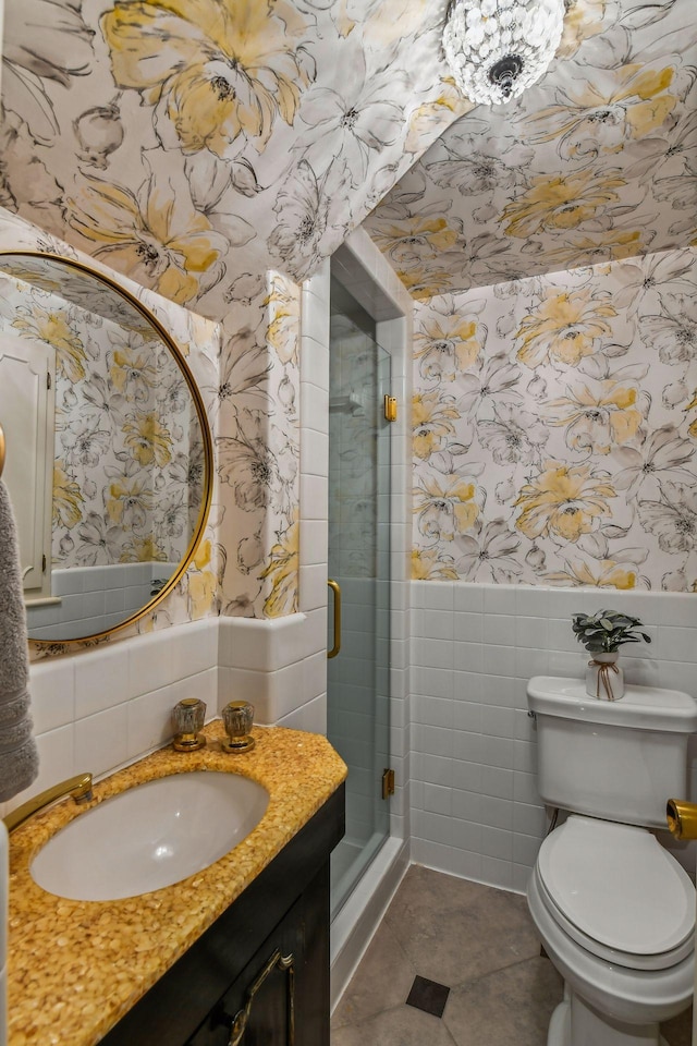 bathroom featuring toilet, a shower with shower door, tile walls, vanity, and tile patterned flooring