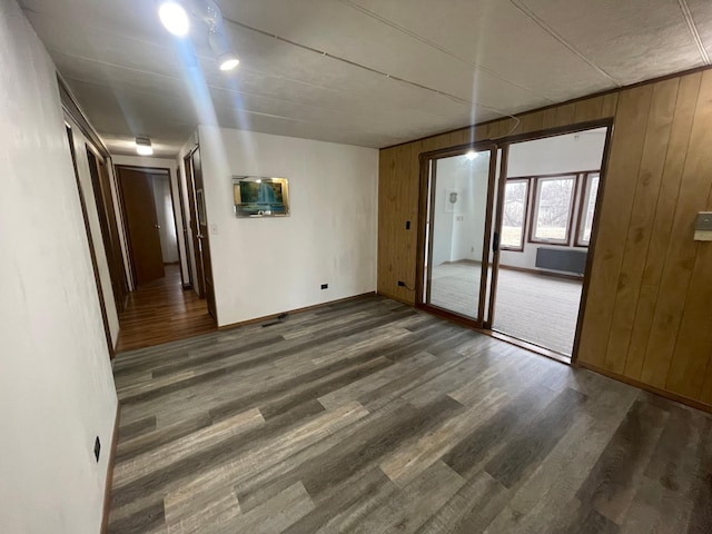 empty room featuring dark wood finished floors, wooden walls, and baseboards