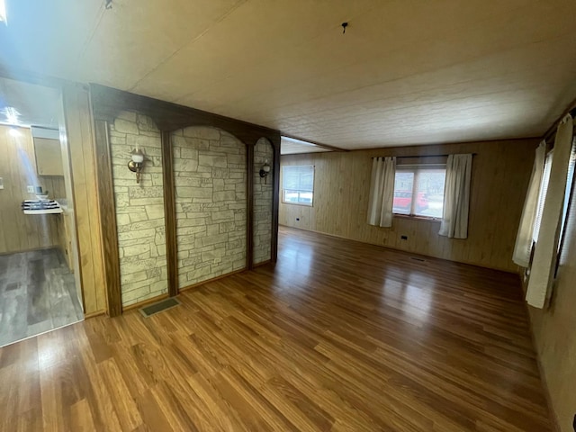 spare room with wood walls, wood finished floors, and visible vents