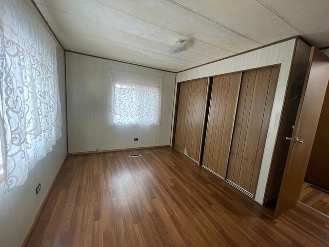 unfurnished bedroom featuring baseboards, crown molding, visible vents, and dark wood-style flooring