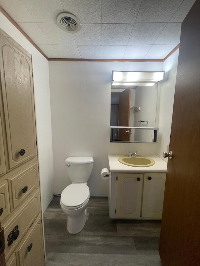 bathroom with toilet, ornamental molding, wood finished floors, and visible vents