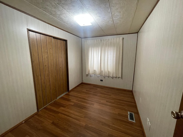 1920 Spruce Ave, Worthington, MN 56187 - unfurnished bedroom featuring wood walls, wood finished floors, a closet, baseboards, and visible vents