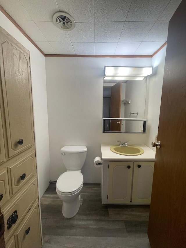 1920 Spruce Ave, Worthington, MN 56187 - bathroom with toilet, visible vents, wood finished floors, vanity, and ornamental molding