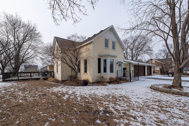 snow covered property featuring a wooden deck and a garage