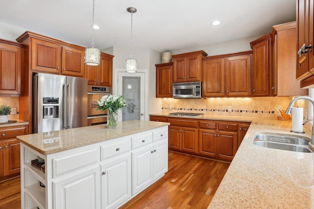 kitchen with sink, a kitchen island, stainless steel appliances, light stone countertops, and white cabinets