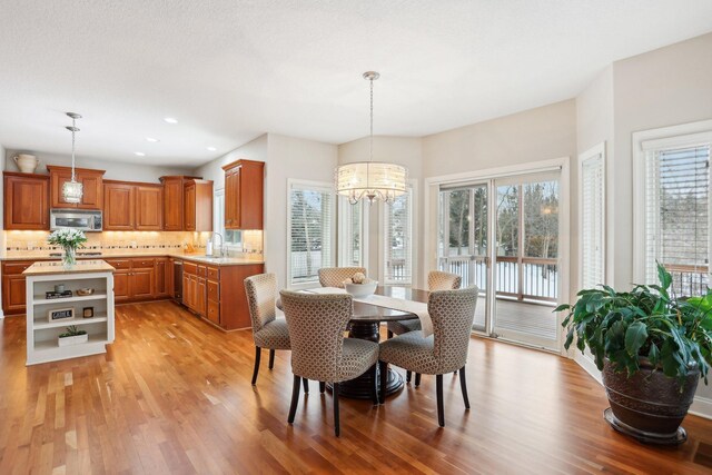 dining space with sink, light hardwood / wood-style floors, and a chandelier