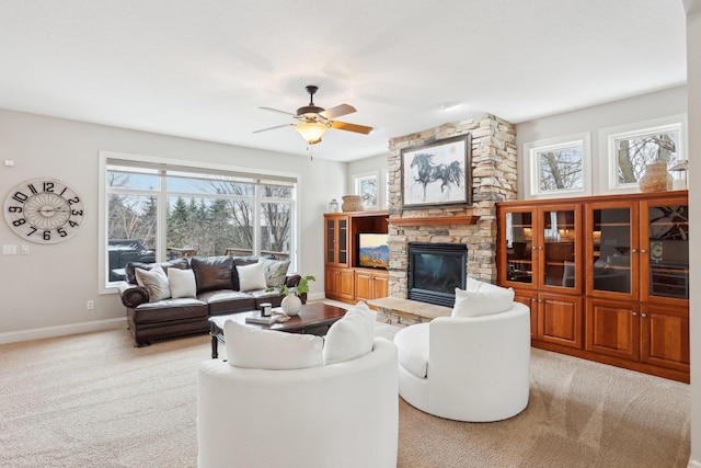 living room with ceiling fan, light colored carpet, and a stone fireplace