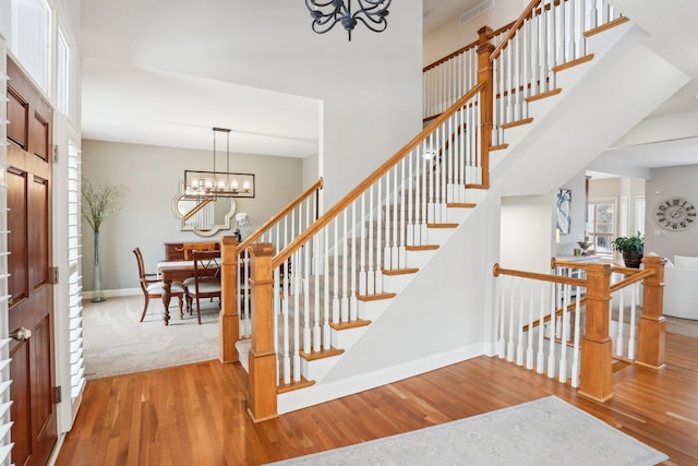 stairway with hardwood / wood-style floors, a notable chandelier, and a towering ceiling