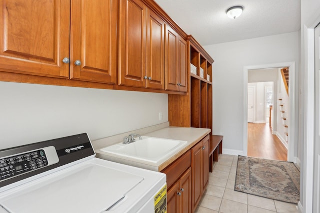 laundry area featuring cabinets, light tile patterned flooring, washer and dryer, and sink