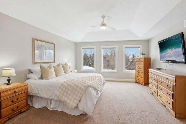 bedroom with ceiling fan, a tray ceiling, and light carpet