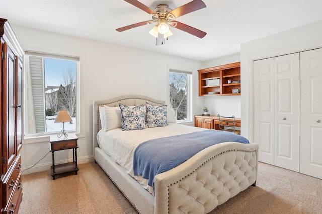 bedroom with ceiling fan, light carpet, and a closet