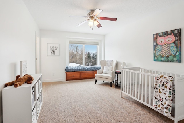 bedroom featuring a crib, carpet, and ceiling fan