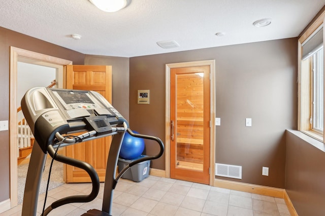 workout room with a textured ceiling and light tile patterned flooring