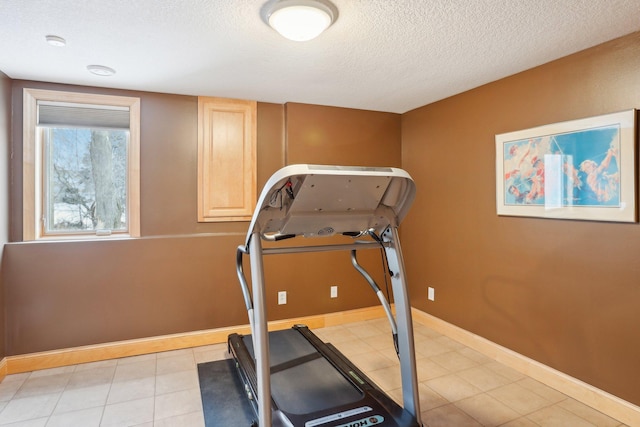 exercise room featuring a textured ceiling and light tile patterned floors