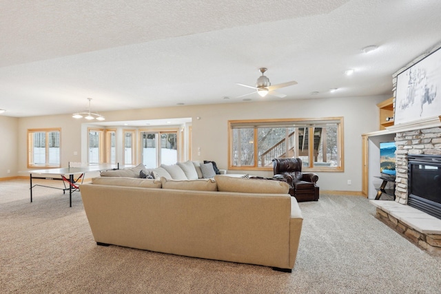 carpeted living room with ceiling fan, a stone fireplace, and a textured ceiling