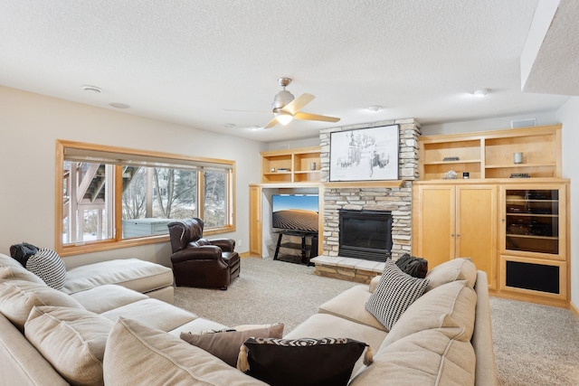 living room featuring ceiling fan, light colored carpet, a textured ceiling, and a fireplace