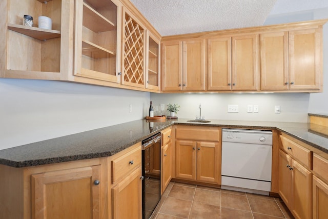 kitchen featuring sink, dark stone countertops, light tile patterned floors, white dishwasher, and a textured ceiling