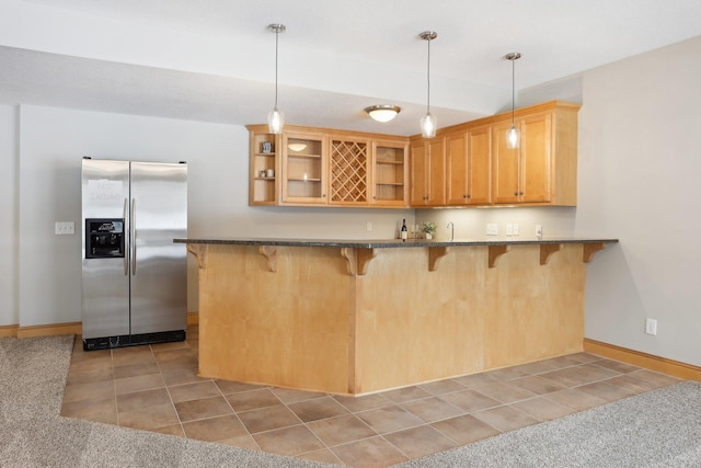 kitchen featuring decorative light fixtures, stainless steel fridge, a kitchen breakfast bar, light tile patterned floors, and kitchen peninsula