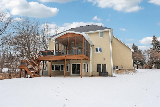 snow covered property with a wooden deck, a sunroom, and central air condition unit