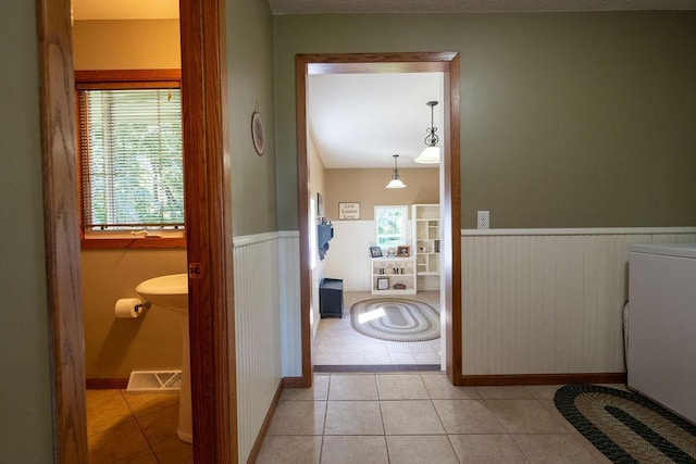 hall featuring a healthy amount of sunlight, washer / clothes dryer, and light tile patterned floors