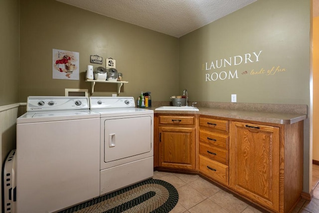 washroom featuring washing machine and clothes dryer, sink, cabinets, a textured ceiling, and light tile patterned floors