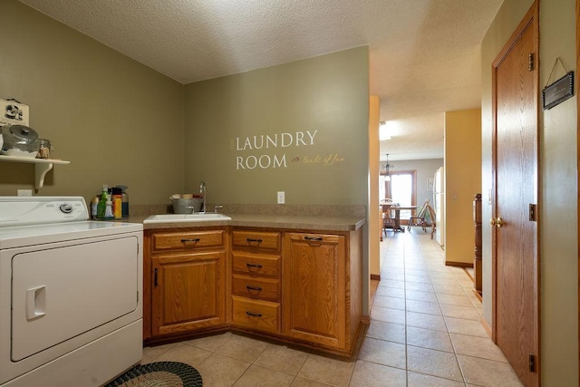 clothes washing area featuring sink, washer / dryer, light tile patterned floors, and a textured ceiling