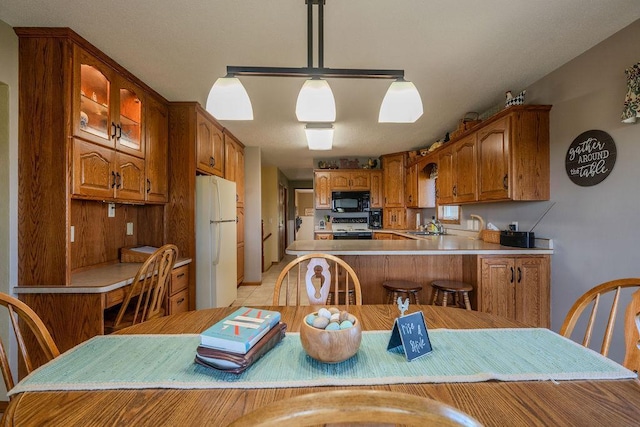 kitchen with sink, decorative light fixtures, white refrigerator, kitchen peninsula, and stove