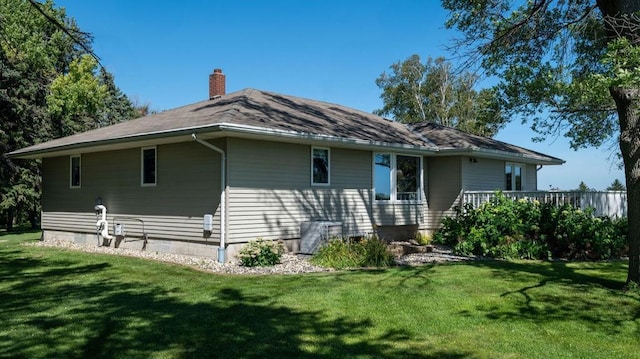 rear view of property with central AC unit and a lawn