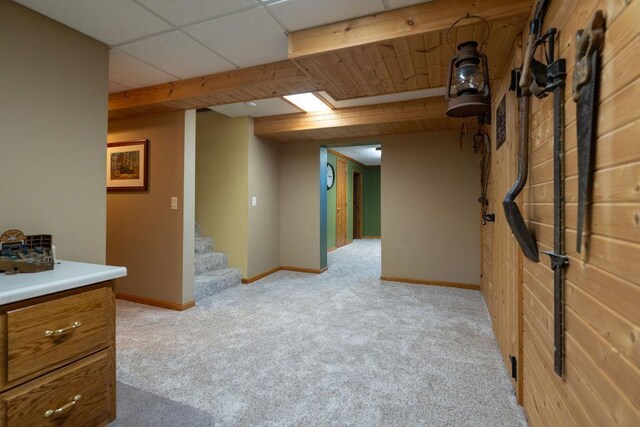 basement with a paneled ceiling and light carpet