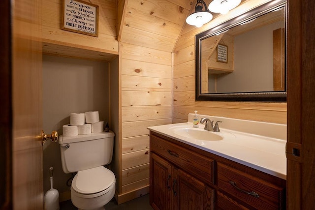 bathroom featuring vanity, wooden walls, and toilet