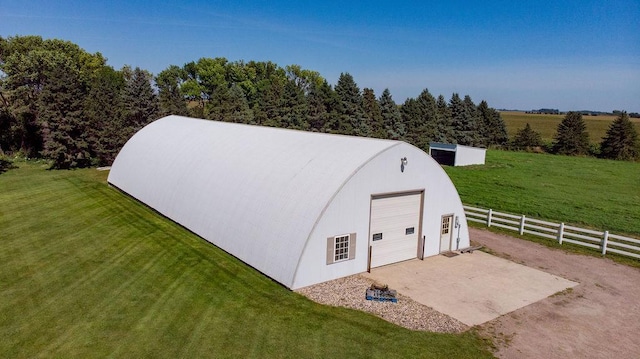 view of outbuilding featuring a rural view, a garage, and a lawn