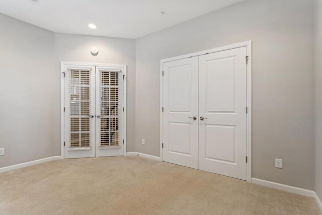 unfurnished bedroom featuring french doors, light colored carpet, and a closet