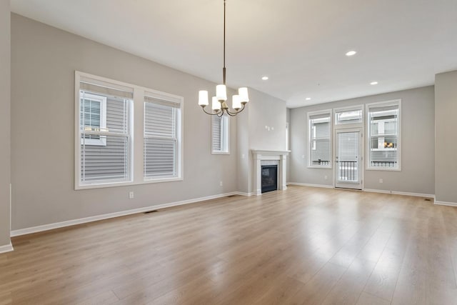 unfurnished living room with a chandelier and light hardwood / wood-style flooring