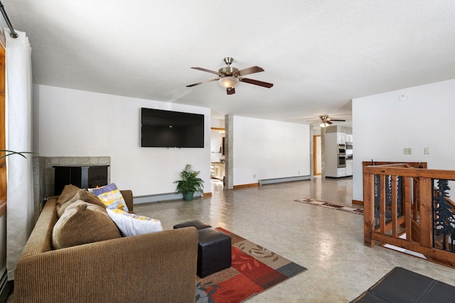 living room featuring a glass covered fireplace, baseboards, a baseboard heating unit, and ceiling fan