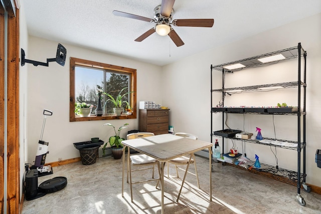 office area featuring concrete flooring, baseboards, a baseboard heating unit, and a ceiling fan