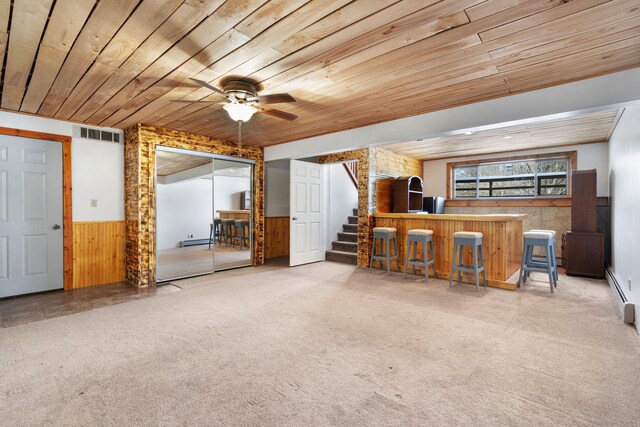 interior space featuring a bar, carpet, wooden ceiling, and wainscoting