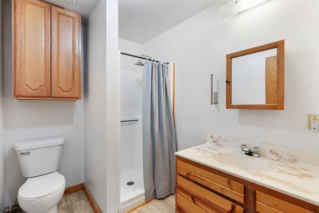 bathroom featuring a shower with curtain, toilet, vanity, and baseboards